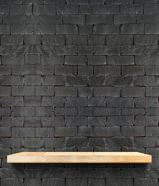 Prateleira de madeira na parede de tijolo preto — Fotografia de Stock