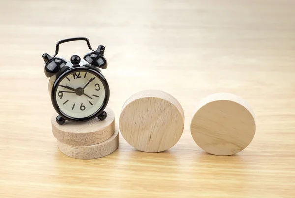 Black alarm clock  on wooden pieces — Stok fotoğraf