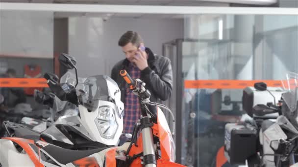 Konsultant rozmawia na telefon w salonie motocyklowego — Wideo stockowe