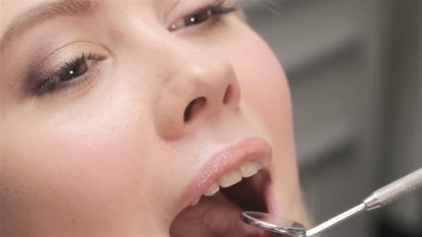 Zubař klade zubní zrcátko do úst pacienta