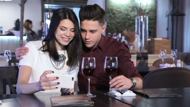 Couple look at smartphone at the restaurant — Stock Video