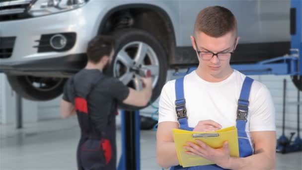 Mechaniker schreibt etwas ins gelbe Logbuch — Stockvideo