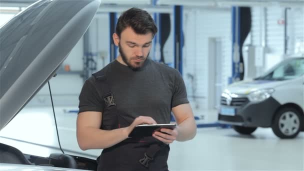 Mecânico usa um tablet no serviço de carro — Vídeo de Stock