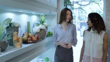 İki kadın yürüyüş çiçekçi, çiçek raf yakınındaki