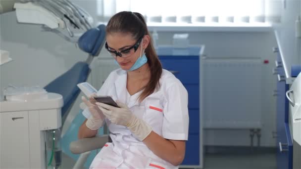 La dentista utilizza il cellulare presso la clinica dentistica — Video Stock