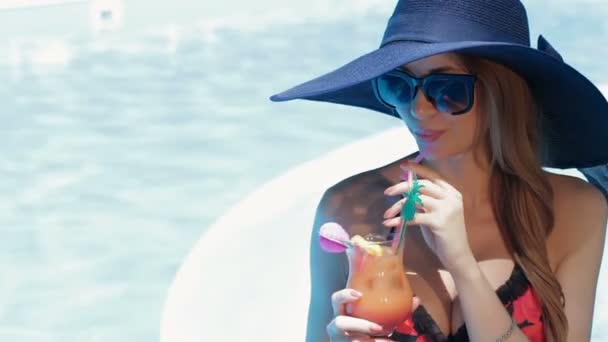 Женщина держит стакан коктейля в руках у бассейна — стоковое видео