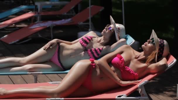 Two women sunbathe near the swimming pool — Stock Video