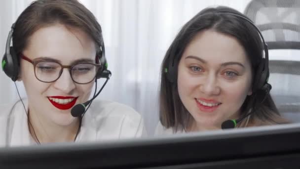 Gesneden opname van twee vrouwelijke call center operators met headsets met behulp van de computer — Stockvideo