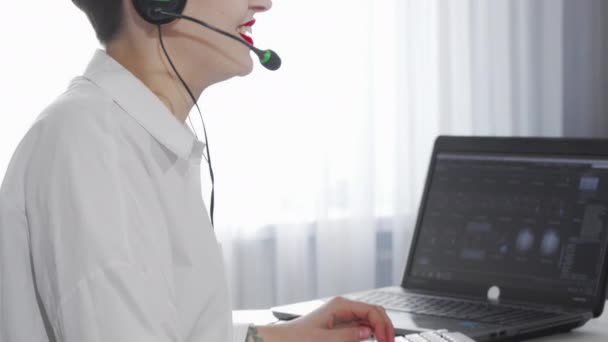 Colpo scorrevole di un operatore di call center femminile che lavora su un computer — Video Stock