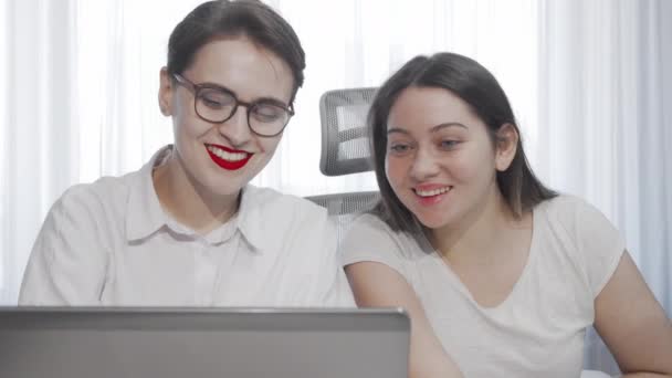 Två kvinnliga frilansare använder laptop samtidigt som de arbetar tillsammans — Stockvideo