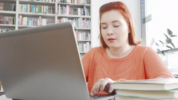 Жінка-студент використовує свій ноутбук у бібліотеці коледжу — стокове відео