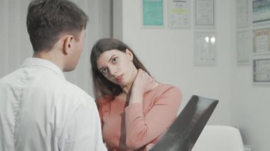 Boyun ağrısı olan bir kadın röntgenden sonra doktoruyla konuşuyor.