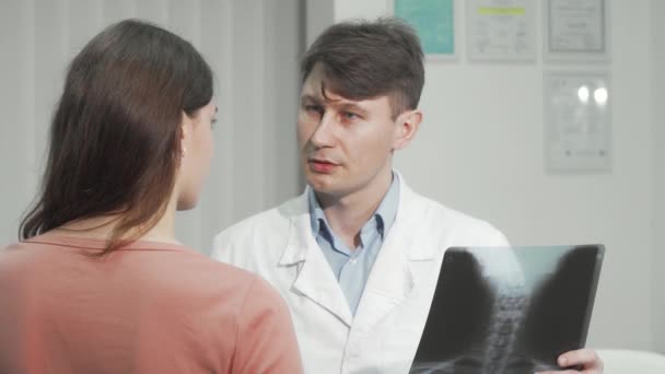 Médecin mature examinant la radiographie spinale d'une patiente — Video