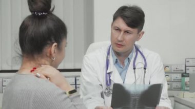 Olgun erkek doktor, kadın hastasıyla konuşuyor.