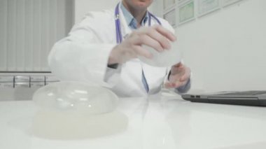 Estetik cerrah, dizüstü bilgisayarında meme implantı örneği tutuyor.