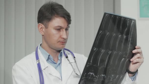 Fröhlich reifer männlicher Arzt lächelt in die Kamera, während er Kernspintomographie untersucht — Stockvideo
