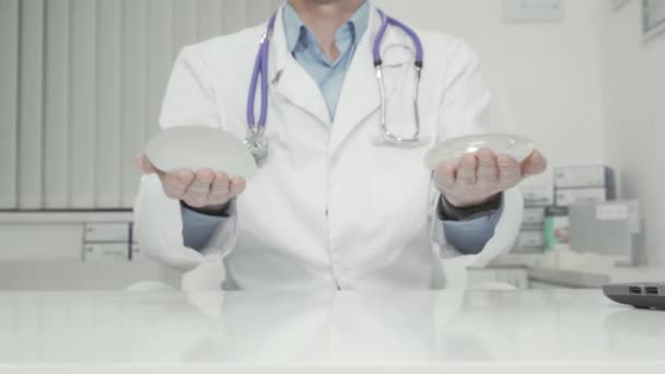Plastic surgeon holding out silicone breast implants to the camera — Stock Video