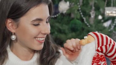 Kameraya gülümseyen neşeli kadın oyuncak Noel Baba 'yı tutuyor.