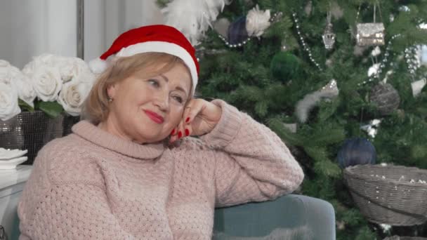 Härlig gammal dam bär jultomte hatt ler bort glatt — Stockvideo