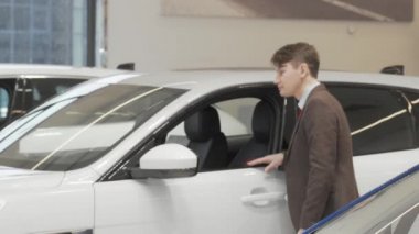 Satış merkezindeki arabaları inceleyen olgun bir adam.