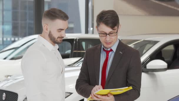 Bel homme signer des papiers chez le concessionnaire après avoir acheté une nouvelle automobile — Video