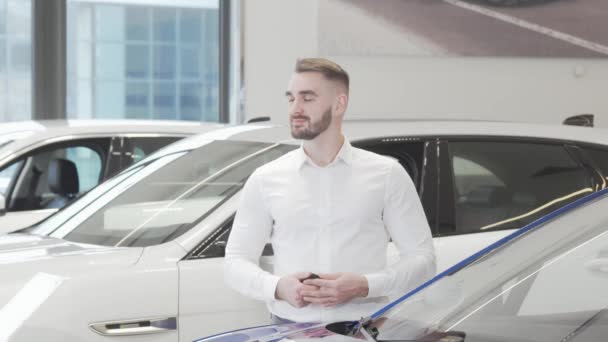 Knappe gelukkige man glimlachend naar de camera staan bij de auto dealer — Stockvideo