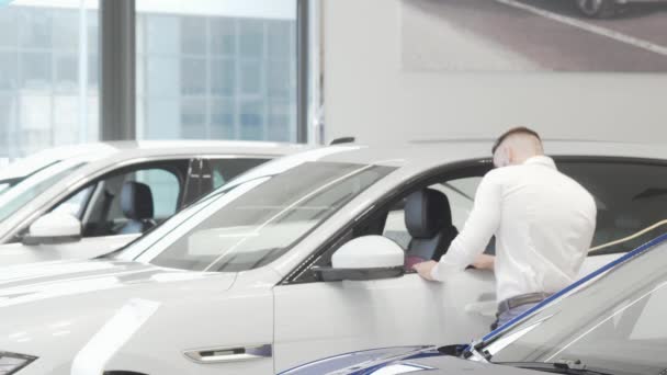 Homme d'affaires attrayant examinant des voitures en vente au salon de concession — Video