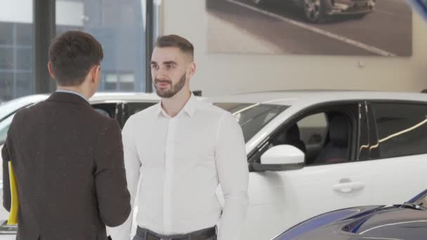Gelukkige jongeman ontvangt autosleutels van zijn nieuwe auto van de verkoper — Stockvideo