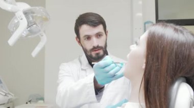 Kadın bir hastanın dişlerini muayene eden profesyonel bir dişçi.