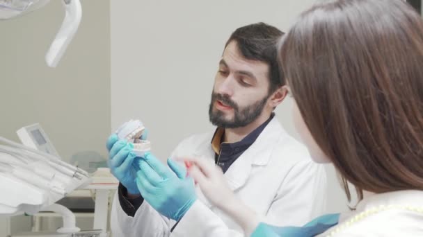 Профессиональный дантист, обучающий свою пациентку во время медицинского осмотра — стоковое видео