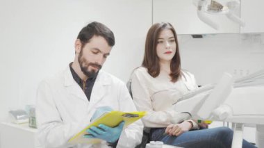 Neşeli dişçi ve kameraya gülümseyen kadın hastası