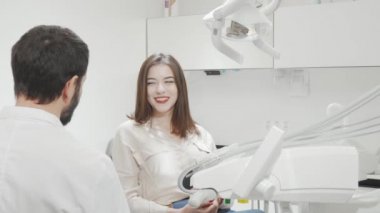 Diş muayenesinden sonra aynaya bakan mutlu kadın.