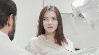 Çekici bir kadın dişçi kliniğindeki aynada dişlerini kontrol ediyor.
