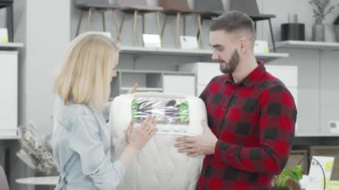 Genç çift ortopedik yatak örneklerini inceliyor.