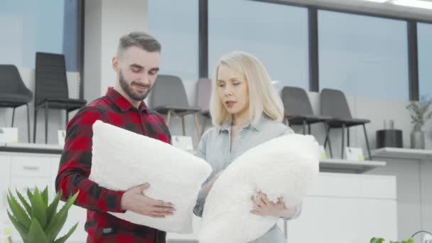 Casal feliz sorrindo para a câmera ao comprar travesseiros na loja de móveis — Vídeo de Stock