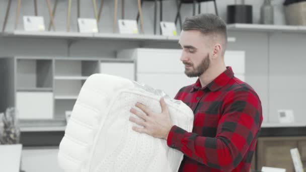 Handsome man examining orthopedic mattress sample at furnishings store — Stock Video