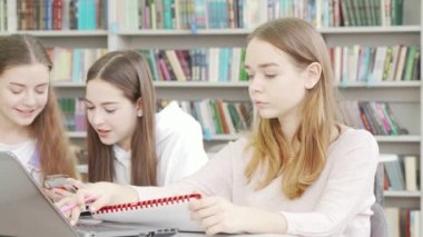 Genç liseli kız kütüphanede bir ödev üzerinde çalışıyor.