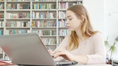 Kütüphanede bilgisayarında çalışan sevimli bir genç kız.