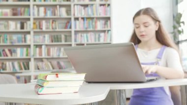 Arka planda dizüstü bilgisayar kullanan kitaplara odaklan.