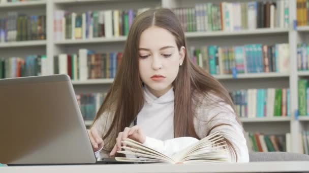 Tonårstjej med dator på biblioteket — Stockvideo