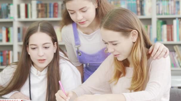 Três meninas adolescentes estudando juntas na biblioteca — Vídeo de Stock