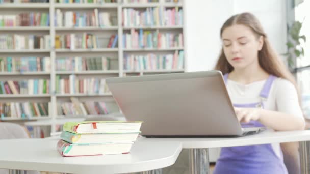 Selektivt fokus på böcker tonåring flicka med bärbar dator på bakgrunden — Stockvideo