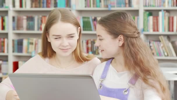 Duas adolescentes gostando de estudar juntas na biblioteca — Vídeo de Stock