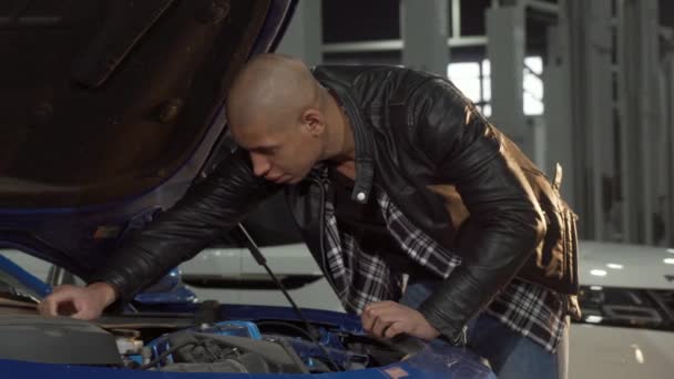 ガレージで彼の車のエンジンを調べている若いアフリカ人男性 — ストック動画