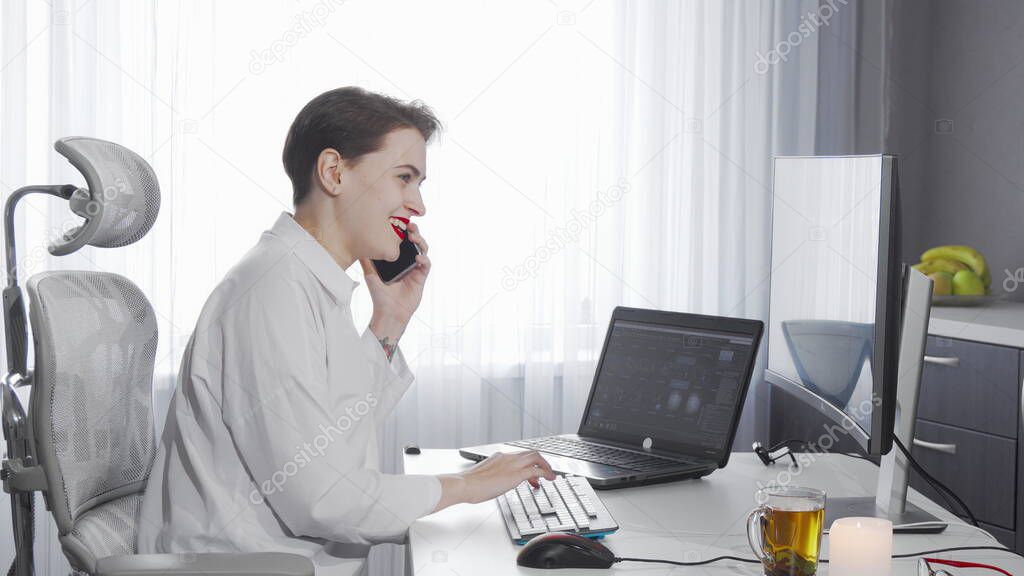 Female entrepreneur talking on her phone while working on two computers