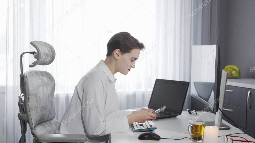 Female freelancer using her smart phone while working on a computer