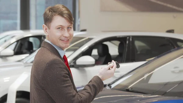 Alegre homem maduro sorrindo para a câmera segurando chaves do carro na concessionária — Fotografia de Stock