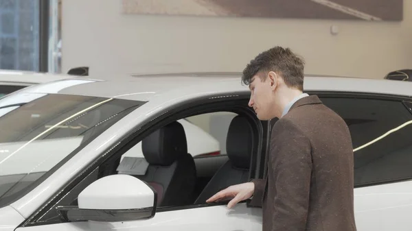Visão traseira tiro de um homem maduro olhando dentro de um carro novo à venda na concessionária — Fotografia de Stock