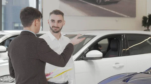 Bonito homem de negócios conversando com vendedor na concessionária de carros — Fotografia de Stock