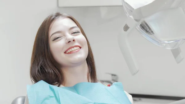 Diş muayenesinden sonra kameraya gülümseyen mutlu genç kadın.